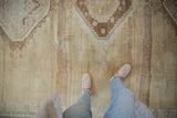Textured vintage Oushak rug pile with abrash and primitive geometric details in earth tones.