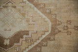 Close-up of distressed Oushak pile with geometric stepped contours in beige and subtle pink.