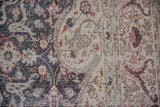 Distressed Sparta rug close-up: worn floral arabesque pattern in charcoal, beige, and rust.