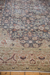 Distressed vintage Sparta carpet close-up: rust and ivory floral arabesque border, wear to knot heads.
