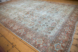 Vintage Mahal carpet corner showing rust and blue border, faded floral vinery field.