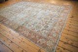 Vintage Mahal rug border with rust and blue floral vinery, revealing worn side edge.