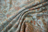 Folded vintage Mahal carpet showing worn floral patterns and border in rust, brown, and slate.