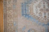 Distressed side selvage and worn pile detail with geometric motifs in abrashed blues and sand.