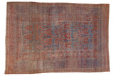 Distressed antique Belouch carpet with geometric germinating plants in faded red and indigo blue.