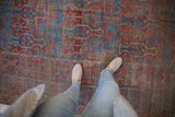 Distressed antique Belouch carpet detail; terracotta and indigo geometric germinating plant motifs, worn texture.