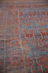 Distressed rich red and blue geometric germinating plant motifs on antique Belouch carpet.