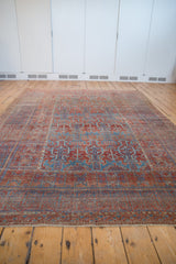 Distressed antique Belouch carpet with geometric plant motifs, textured wear, and rich red, blue hues.
