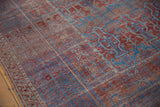 Distressed antique Belouch carpet's side selvage and geometric patterns in terracotta and blue with wear.