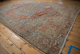 Angled view of a distressed vintage Heriz rug, displaying worn brick red and powder blue patterns.