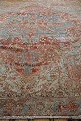 Distressed Heriz rug close-up: geometric motifs, worn texture, brick red, and denim blue palette.