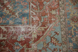 Distressed vintage Heriz carpet: worn brick red and powder blue geometric spandrel, foundation visible.