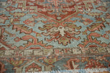 Close-up of vintage distressed Heriz carpet showcasing worn texture, light blue and brick red patterns.