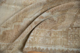 Distressed Kars carpet's short pile with abrashed beige texture and partial geometric border.