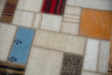 Intricate seaming and varied textures of blue, orange, and red Turkish patchwork rug sections.
