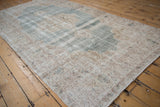 Distressed Vintage Sparta carpet corner with pale blue abrashed field and mostly even pile wear.