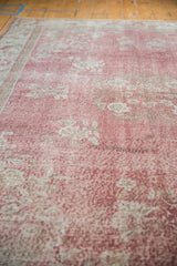 Distressed texture of the Sparta carpet with soft rose blush and faded ivory florals.