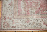 Worn pile of a distressed Sparta carpet, showing faded rose and gray curvilinear border.