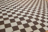 Tight hand-woven texture of ivory and chocolate brown checkered blocks on Indian Kilim rug.