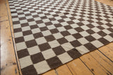 Geometric ivory and chocolate brown checkered Indian Kilim carpet edge with intact selvage.