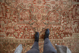 Distressed vintage Persian Heriz rug showing geometric arabesques and worn pile.