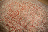 Distressed Heriz carpet with textured geometric patterns in softened red, ivory, and beige.