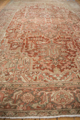 Distressed Heriz carpet border detail, showing time-softened red, ivory, and beige geometric patterns.