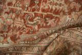 Folded vintage Heriz rug, with distressed geometric patterns in muted red and beige tones.