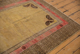 Antique Khotan rug's charcoal geometric border, pale raspberry band, and running T motif.
