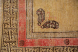 Antique Khotan rug with charcoal geometric border, pale raspberry band, and butterfly motif.