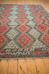 Afghani Kilim rug's charcoal outer border featuring zig-zag vine, floral blossoms, and fringe.