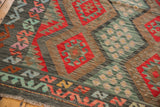 Afghani Kilim detail with serrated palmettes, geometric bouquet, and zigzag border in charcoal, cherry red, and dusty blue.