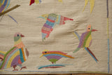 Colorful striped birds with raised embroidered stitching on a textured ivory kilim.