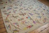 The raised textural stitching of colorful birds on a handwoven Pakistani kilim carpet.