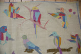 Colorful pictorial birds in flight and perched, detailed with raised stitching on a kilim rug.