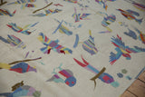 Raised-stitch bird motifs in blue, yellow, and mauve on a textured ivory Pakistani kilim.