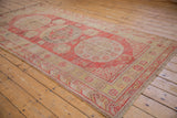 Vintage Khotan runner corner, showing dusty red wave and cloud border, side selvage, and abrash.