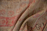 Folded vintage Khotan rug runner detail: pale cherry red palmettes on worn beige pile.