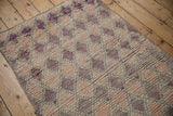 Moroccan rug's distressed pile showing softened trellis pattern with purple and rose abrashes.