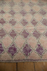 Textured pile of distressed Moroccan runner, with dynamic purple, pink, ivory geometric diamond motif.