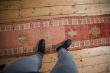 Vintage distressed Anatolian runner, dusty cochineal abrash, serrated palmettes, and leaf border.