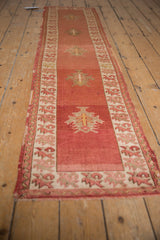Distressed Anatolian runner: cochineal red abrash field, serrated palmette, geometric ivory border.