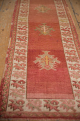 Distressed Anatolian runner showcasing serrated palmette motifs on dusty cochineal red field.