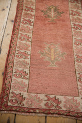 Distressed cochineal red field of vintage Anatolian runner with central palmette.