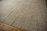 Vintage distressed Turkish Sparta carpet corner showing muted ivory and silver scrolling vines with even wear.
