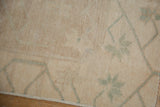 Distressed Oushak rug pile, featuring pale green trellis floral buds, even wear, and secured edge.