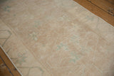 Distressed beige pile with faded pale green floral buds on a vintage Oushak rug.