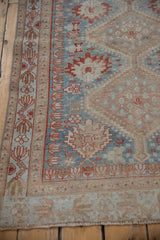 Distressed corner of vintage Afshar rug, showcasing madder root palmette border and sky blue field.