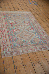 Corner detail of distressed Afshar rug with madder root and sky blue patterns, faded fringe.