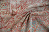 Folded distressed vintage Karaja rug, showing faded red, pale blue geometric patterns and wear.